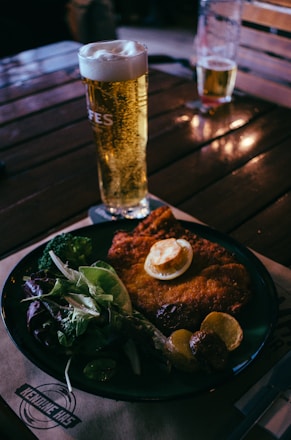 a plate of food and a glass of beer on a table