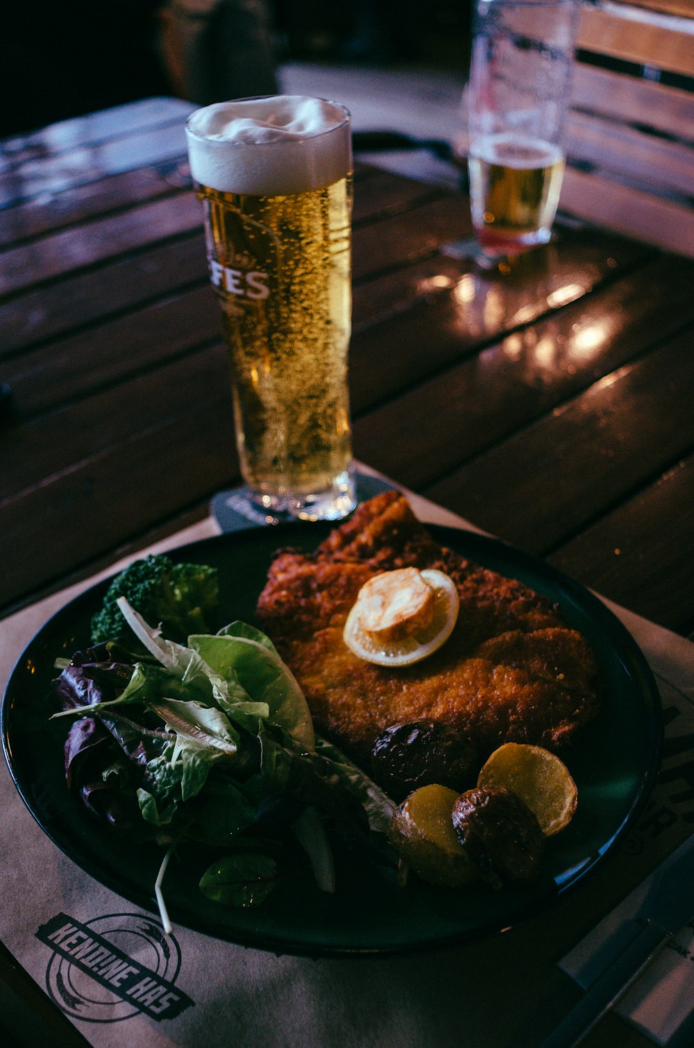 um prato de comida e um copo de cerveja em uma mesa