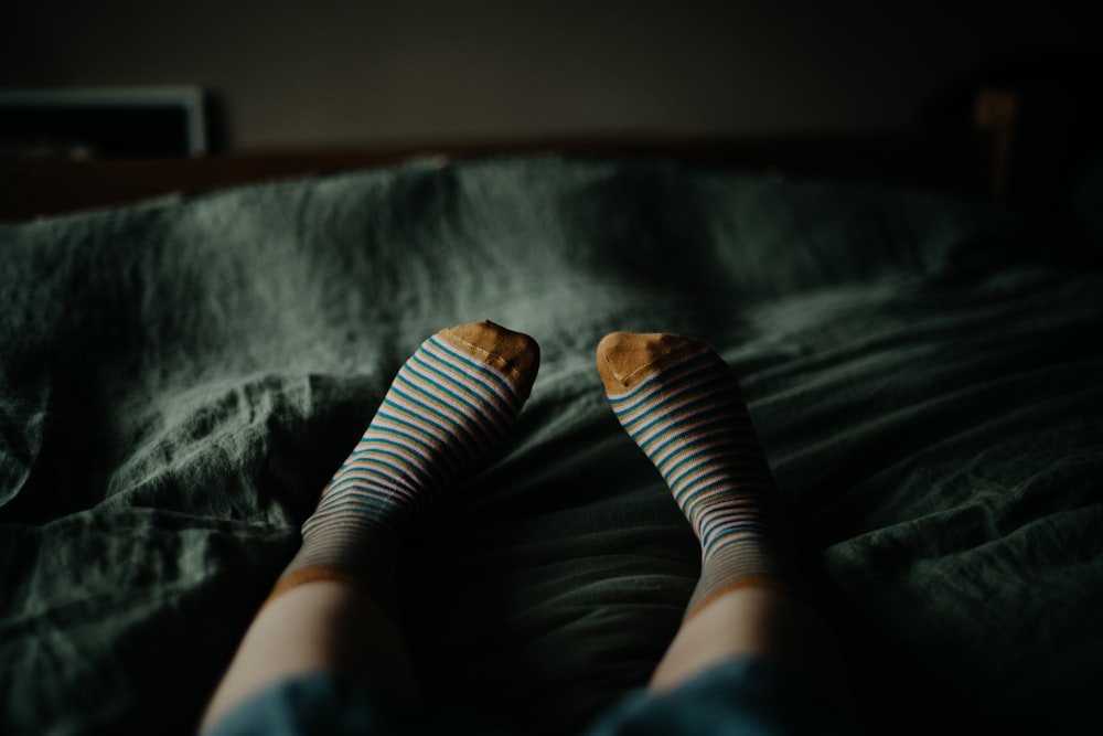 a person with striped socks laying on a bed