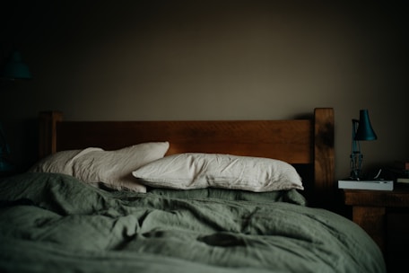 a bed with a green comforter and pillows