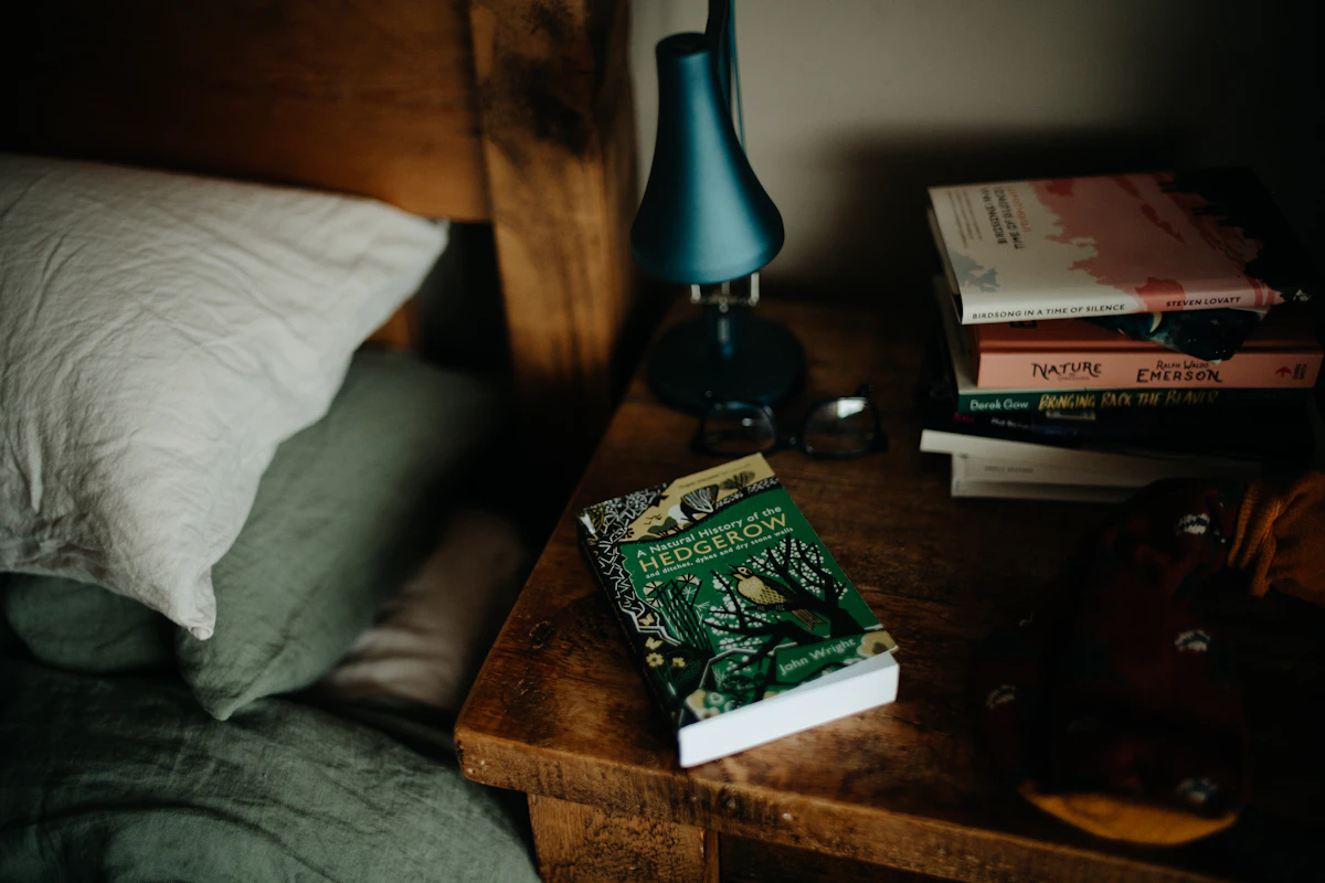 Books on a bed beside a soft lamp