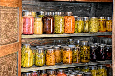 Close-up of fresh vegetables and preserved jars arranged on a weathered farmhouse shelf