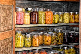 A cozy kitchen scene with jars of colorful homemade fermented vegetables on a wooden shelf.