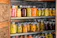 A cheerful woman proudly showing her jars of homemade canned vegetables in a bright kitchen.