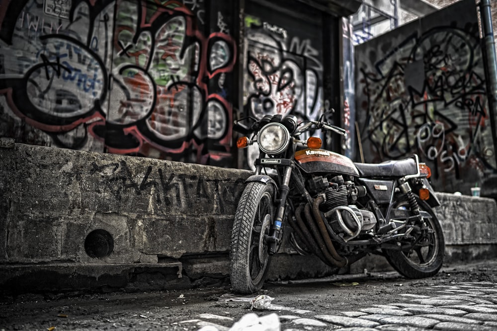 a motorcycle parked next to a wall with graffiti on it