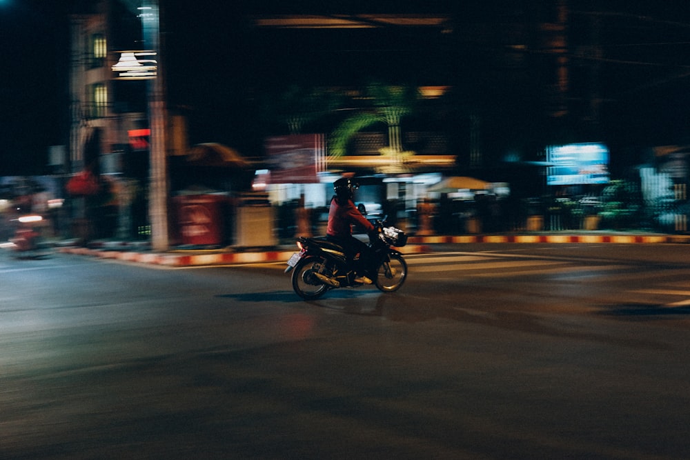 a man riding a motorcycle down a street at night