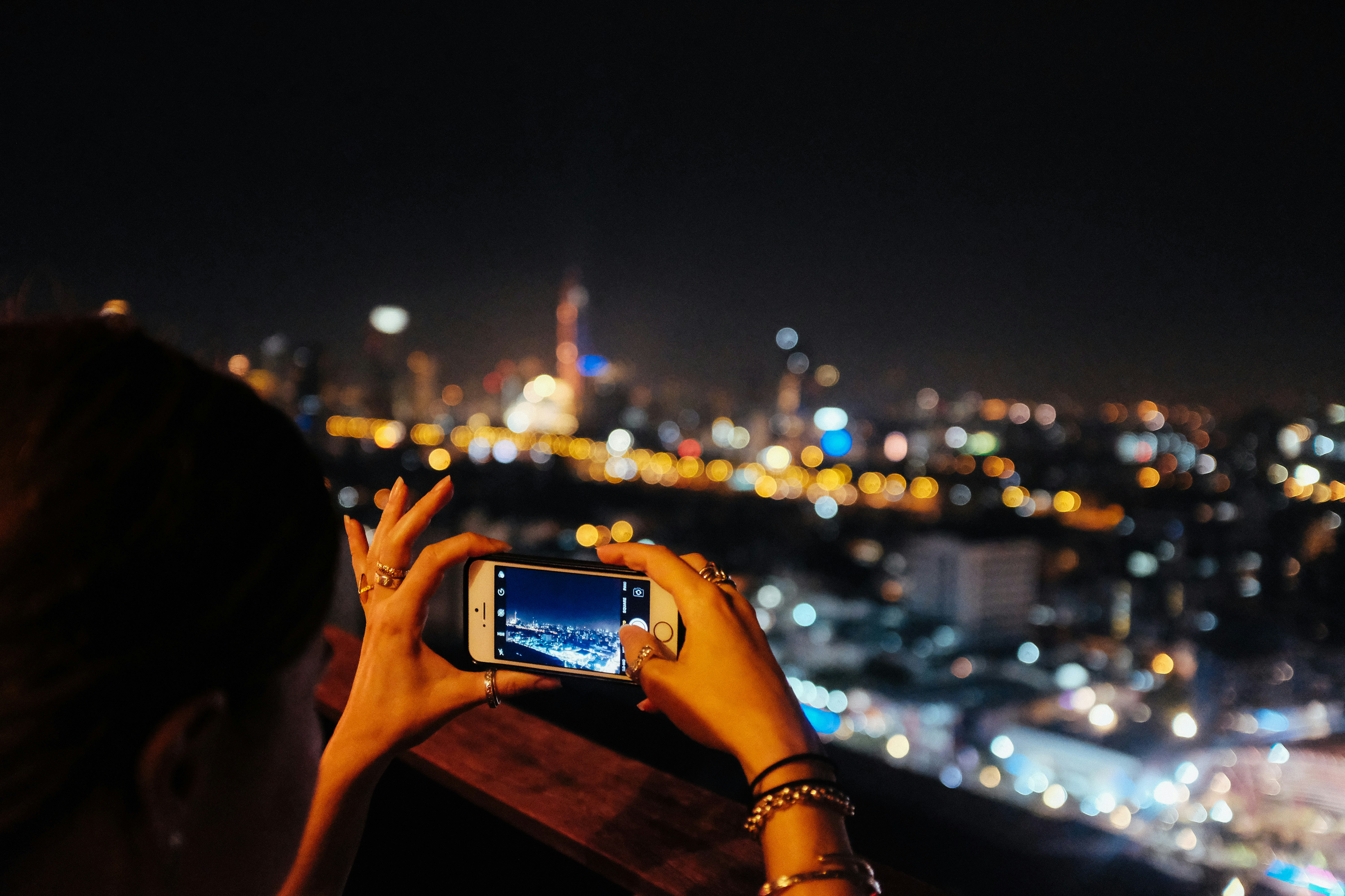 a woman taking a picture of a city at night