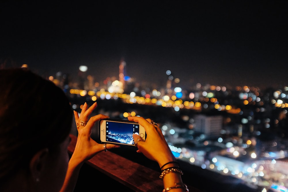 uma mulher que tira uma foto de uma cidade à noite