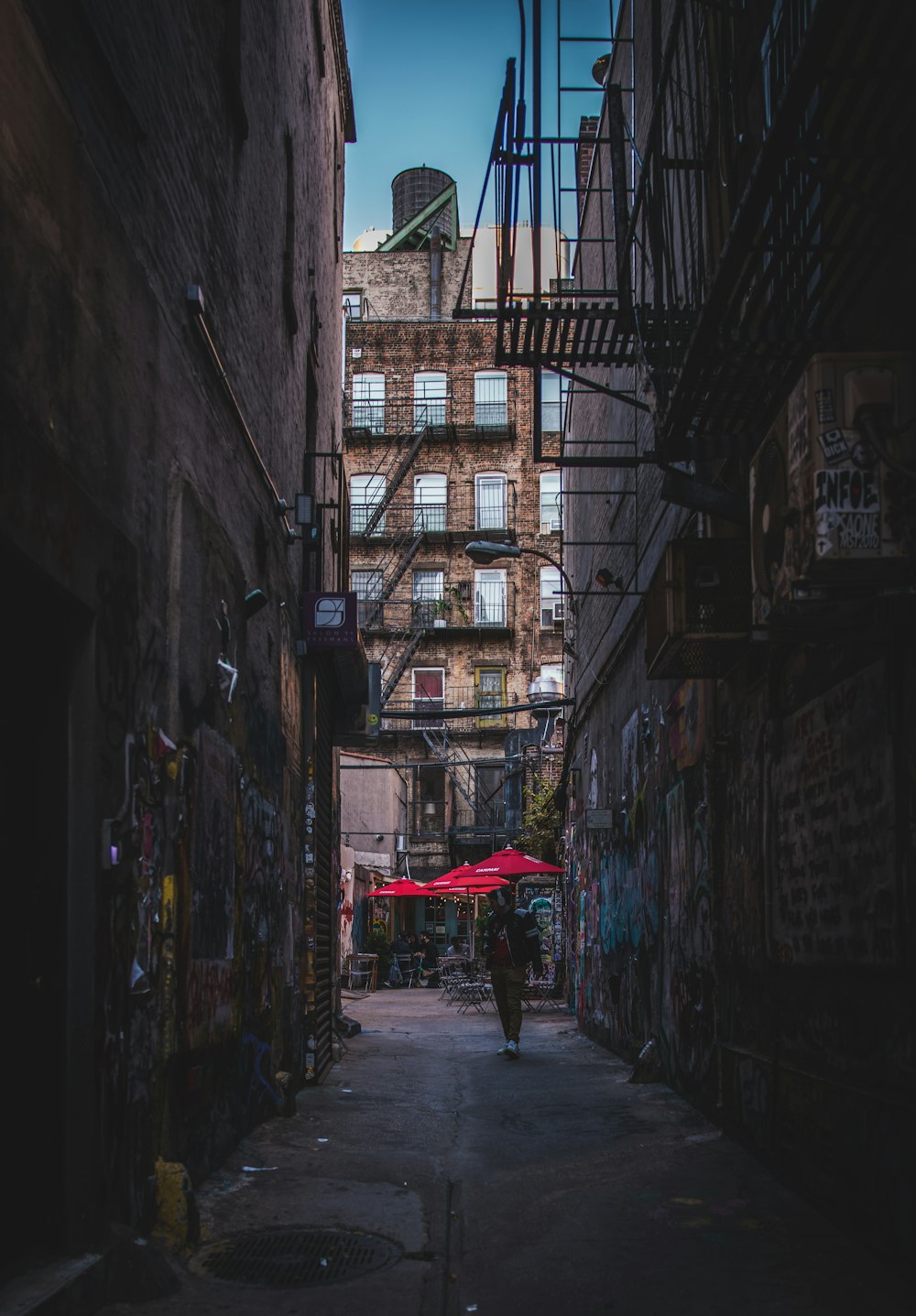 a person walking down an alley way with a red umbrella