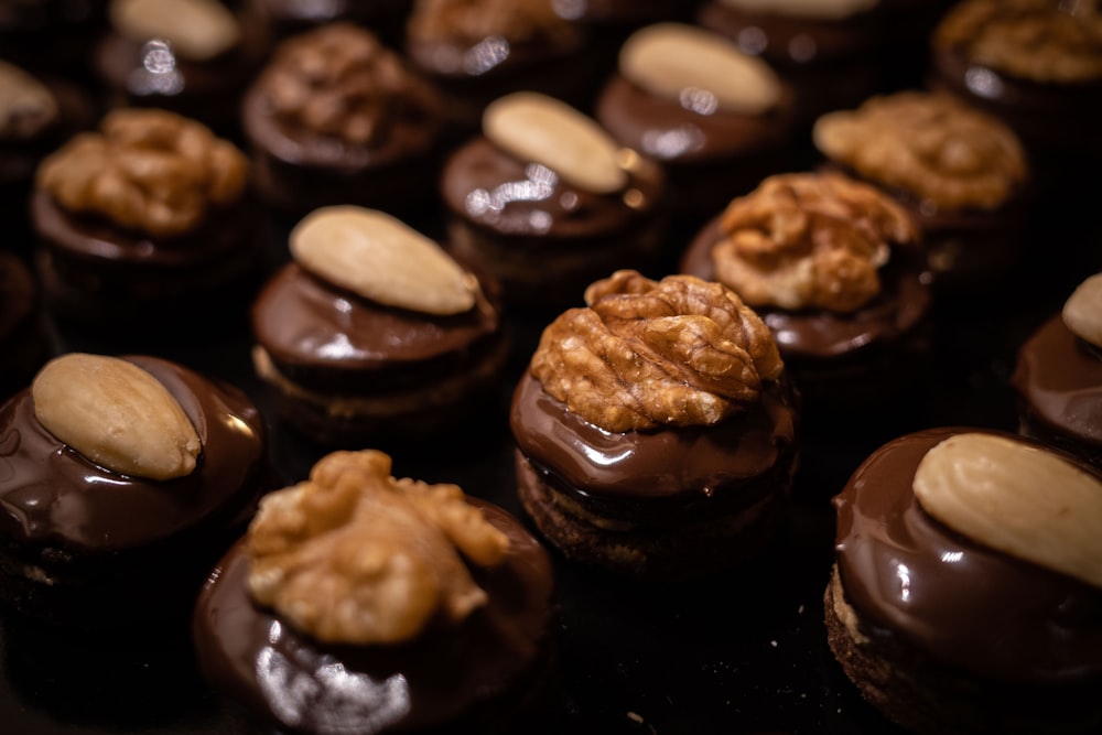 a close up of many chocolates with nuts on top