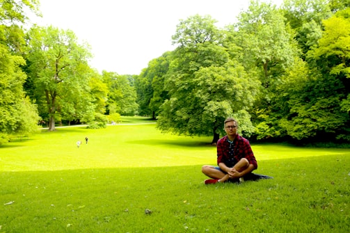 a man sitting on top of a lush green field