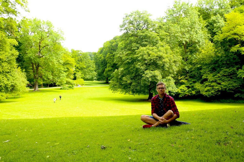 a man sitting on top of a lush green field