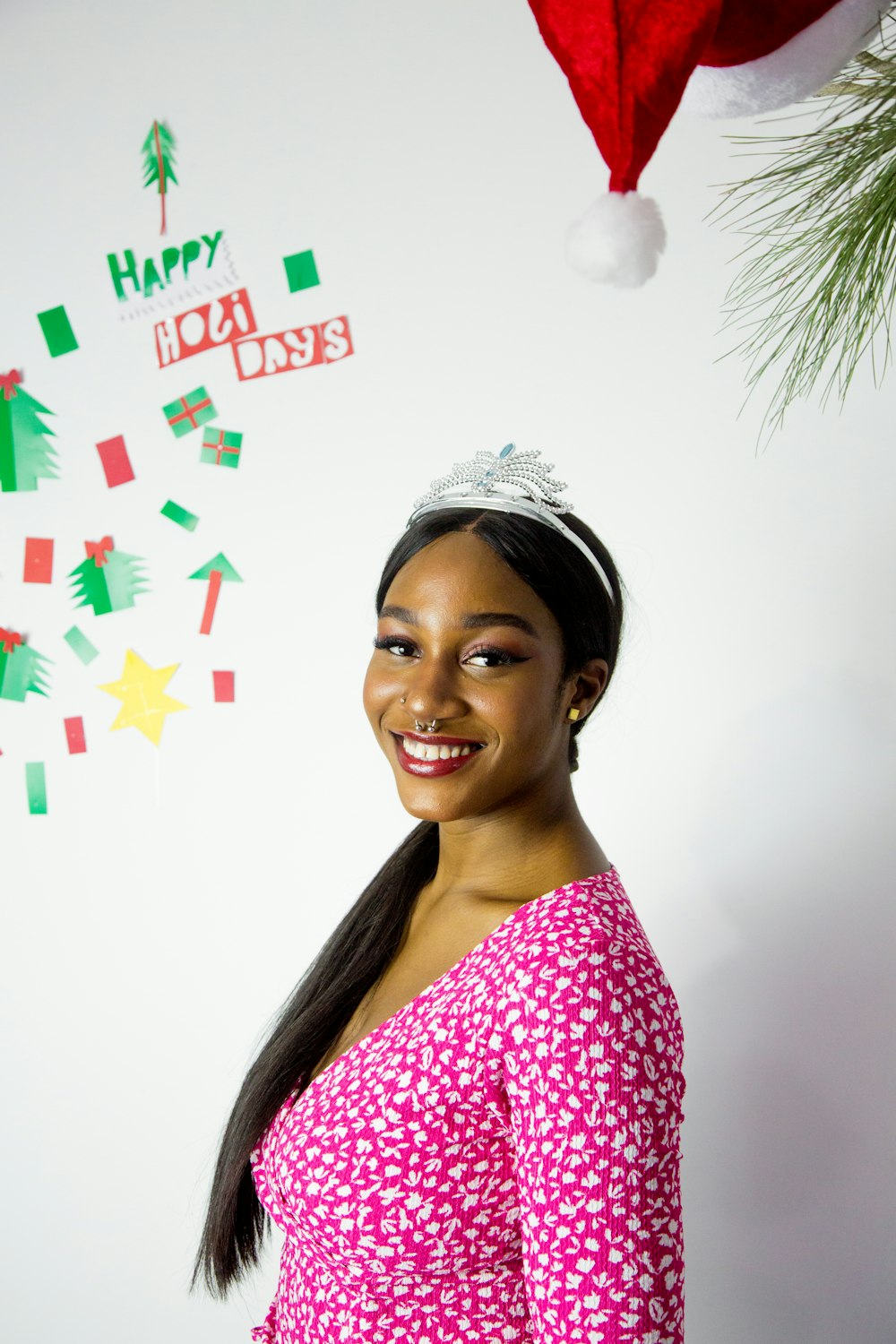 a woman wearing a tiara standing in front of a christmas tree