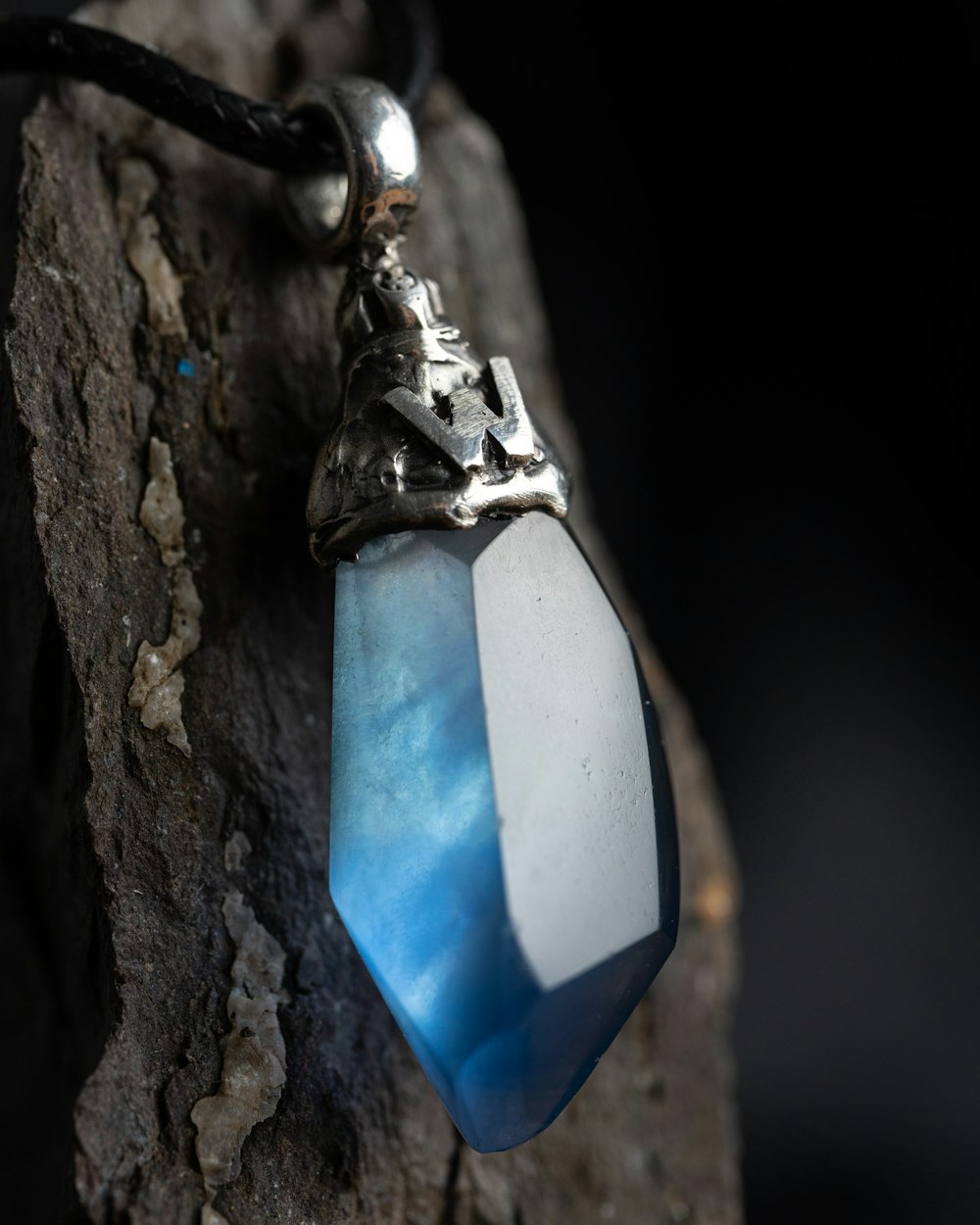 una collana con una pietra blu e bianca appesa a una corda di cuoio