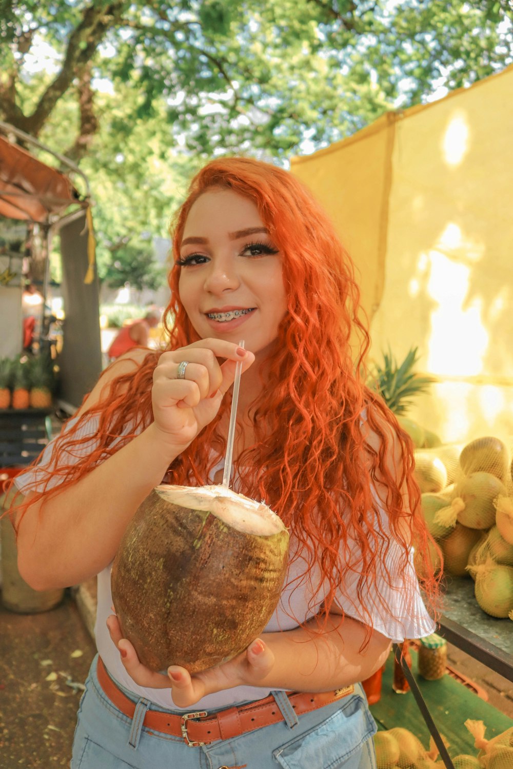 a woman holding a coconut and a straw in her hand