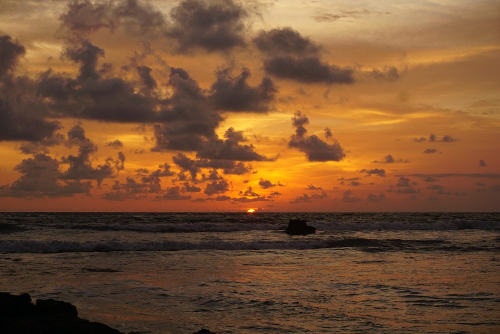 a sunset over the ocean with a boat in the water