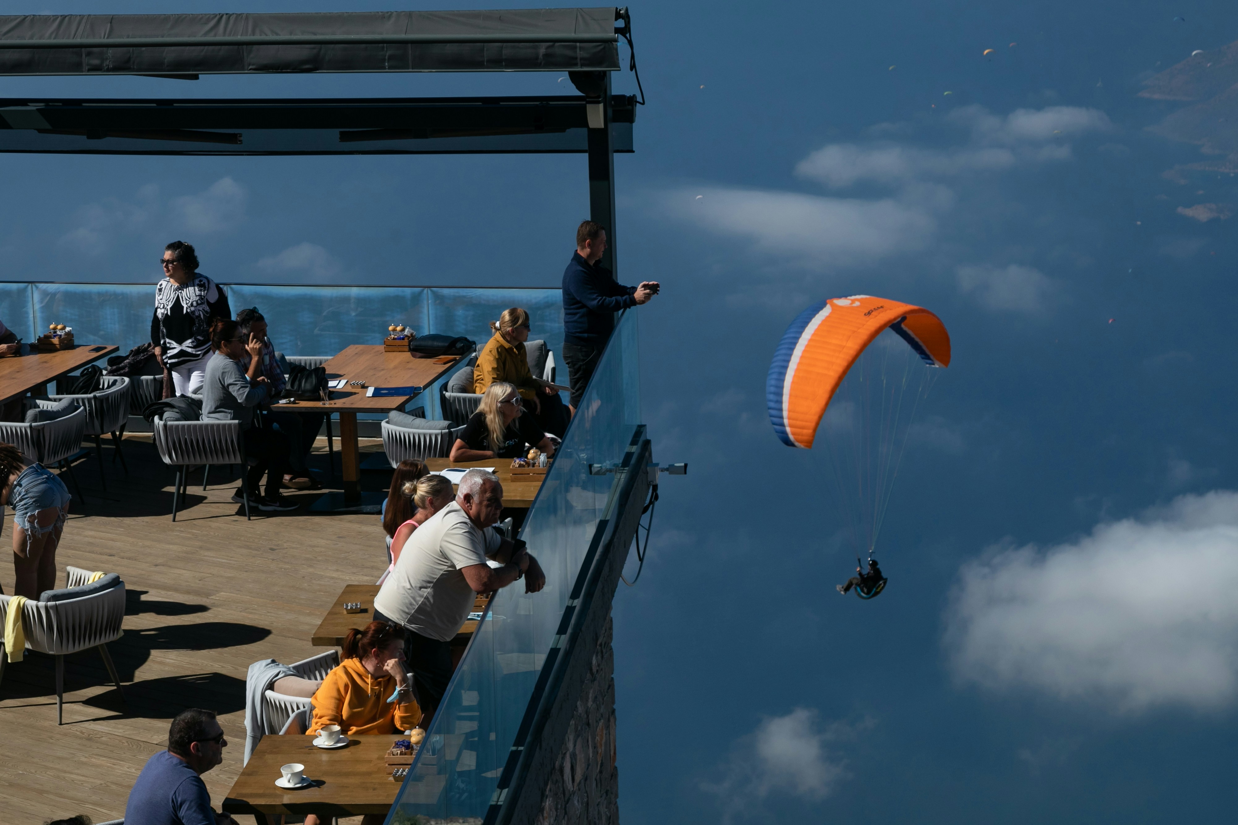 a group of people sitting at a table with a parasail in the sky
