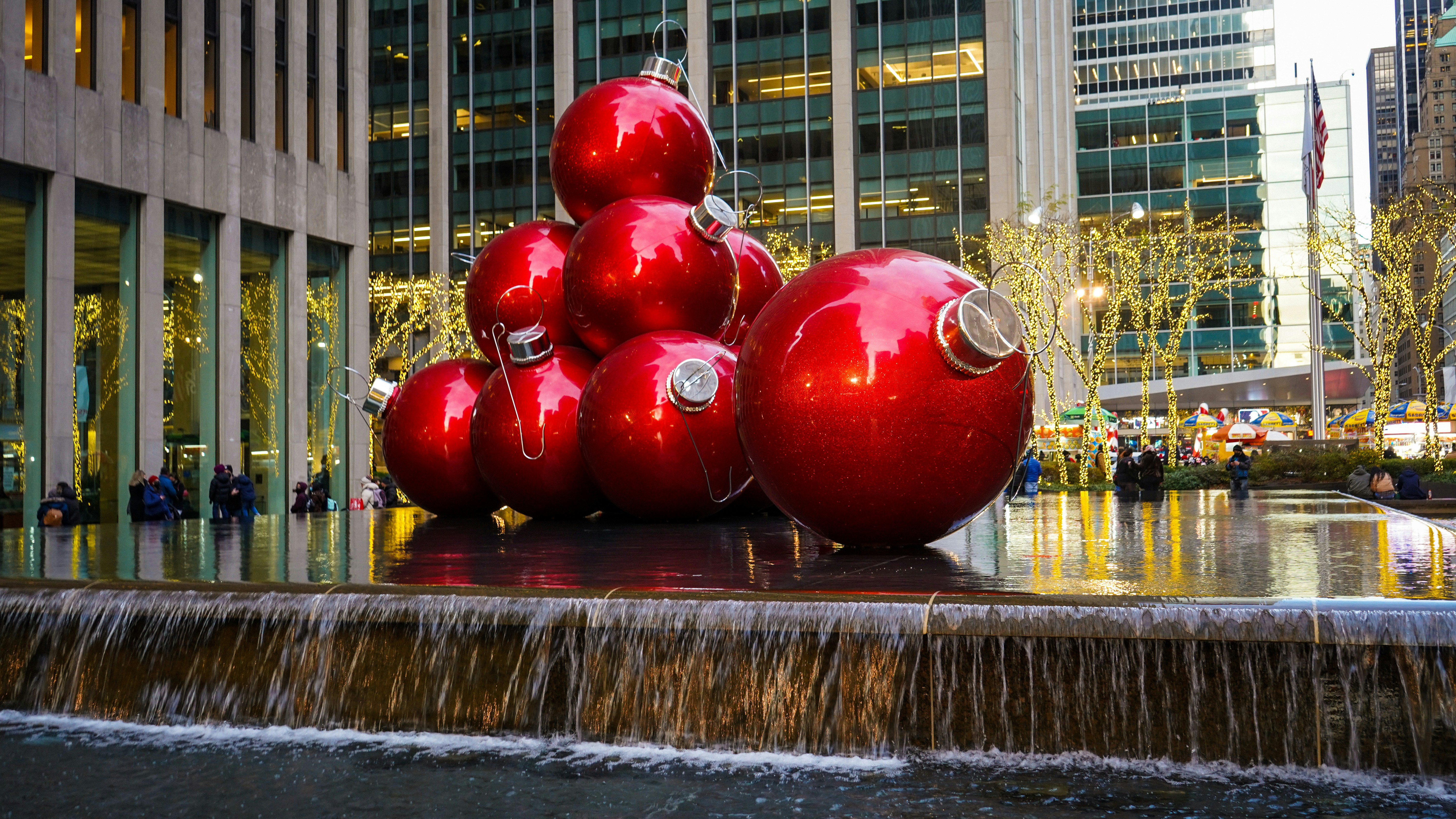a group of red balls sitting on top of a fountain, giant red christmas decorations, new york, dec 2021