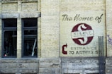 A brick wall with a large sign painted on it displaying the name 'Silco Industries Ltd.' along with an arrow pointing towards the entrance at 70 Arthur St. The wall is part of an older building with two large windows and visible pipes, adding an industrial vibe.