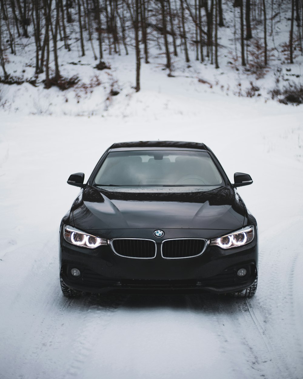 a black car driving down a snow covered road