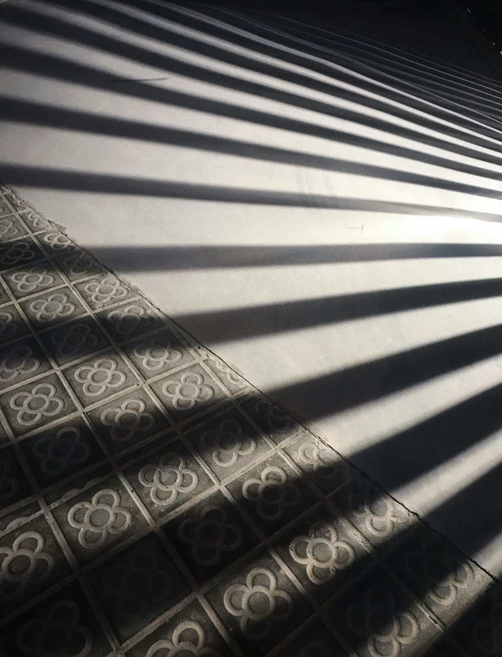 the shadow of a building on a tiled floor