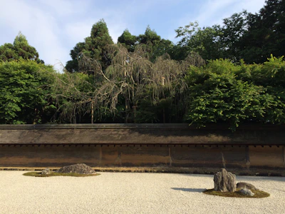 A serene Japanese rock garden with raked gravel and smooth stones under soft morning mist.