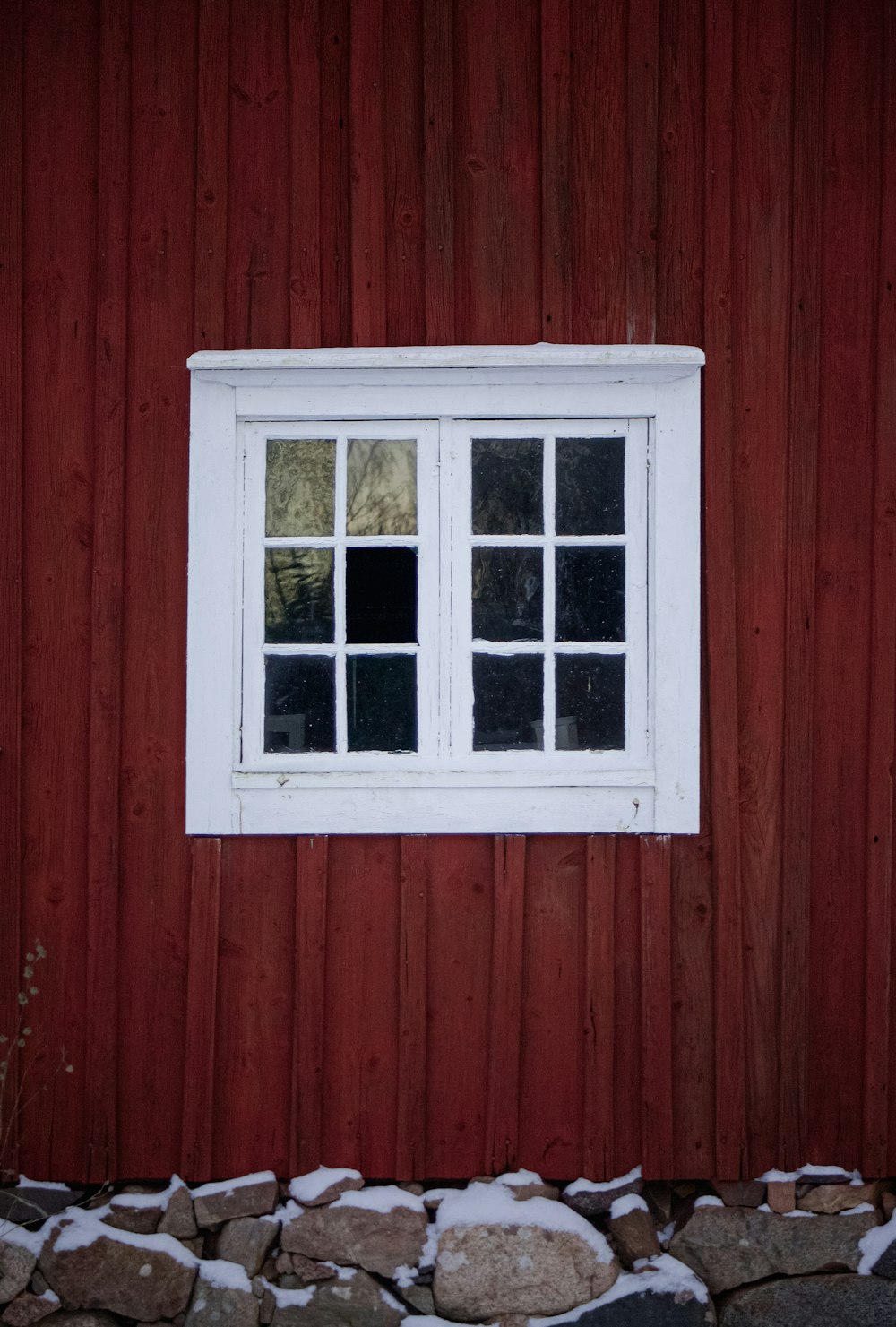 a red building with a white window and snow on the ground