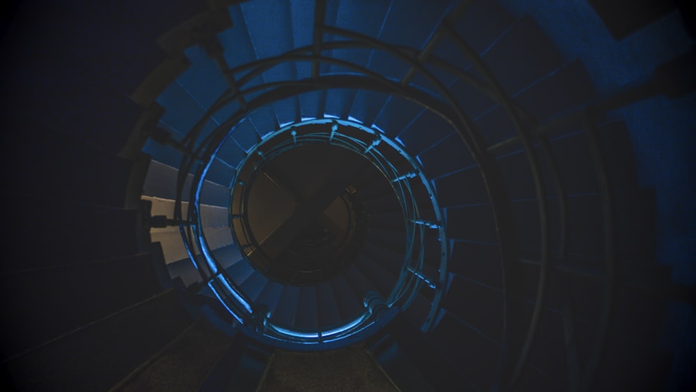 a spiral staircase in a dark room with blue lights