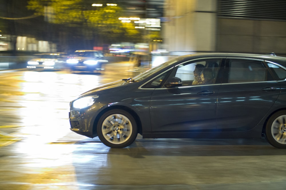 a blue car driving down a city street at night