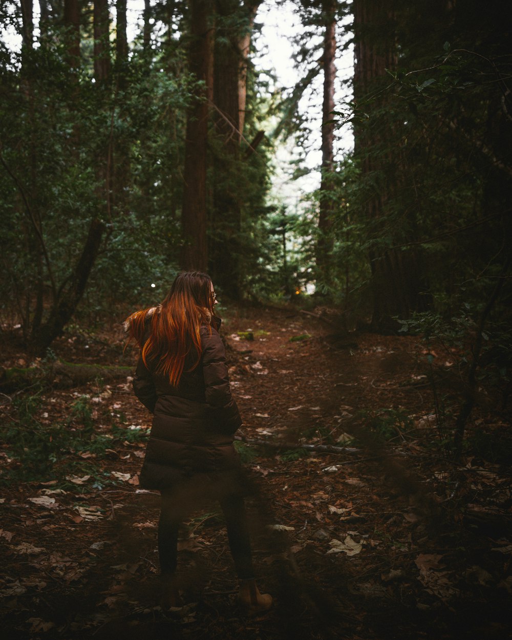 a woman standing in the middle of a forest