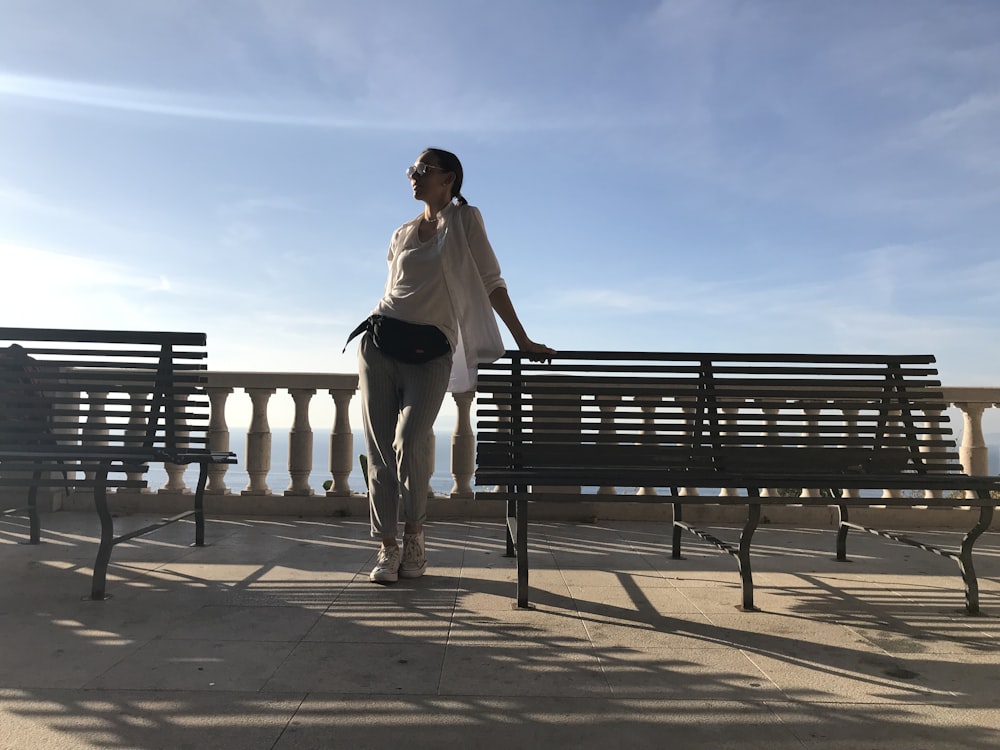 a woman standing next to a wooden bench