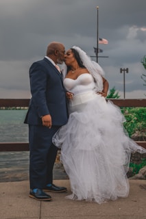 a bride and groom kissing on a pier