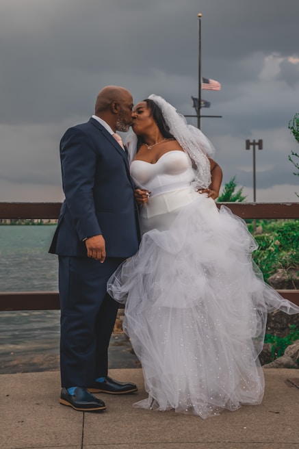 a bride and groom kissing on a pier