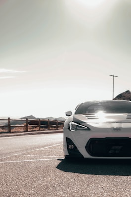 An exotic car gleaming under soft sunlight on a winding mountain road.
