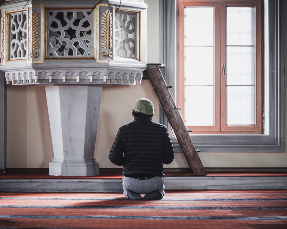 a man sitting on the floor in front of a clock