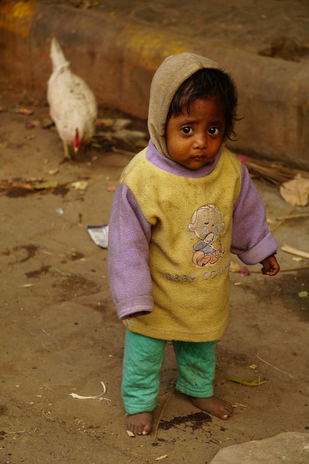 a small child in a yellow shirt and green pants