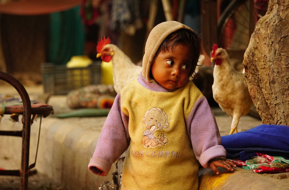 a little girl standing next to a bunch of chickens