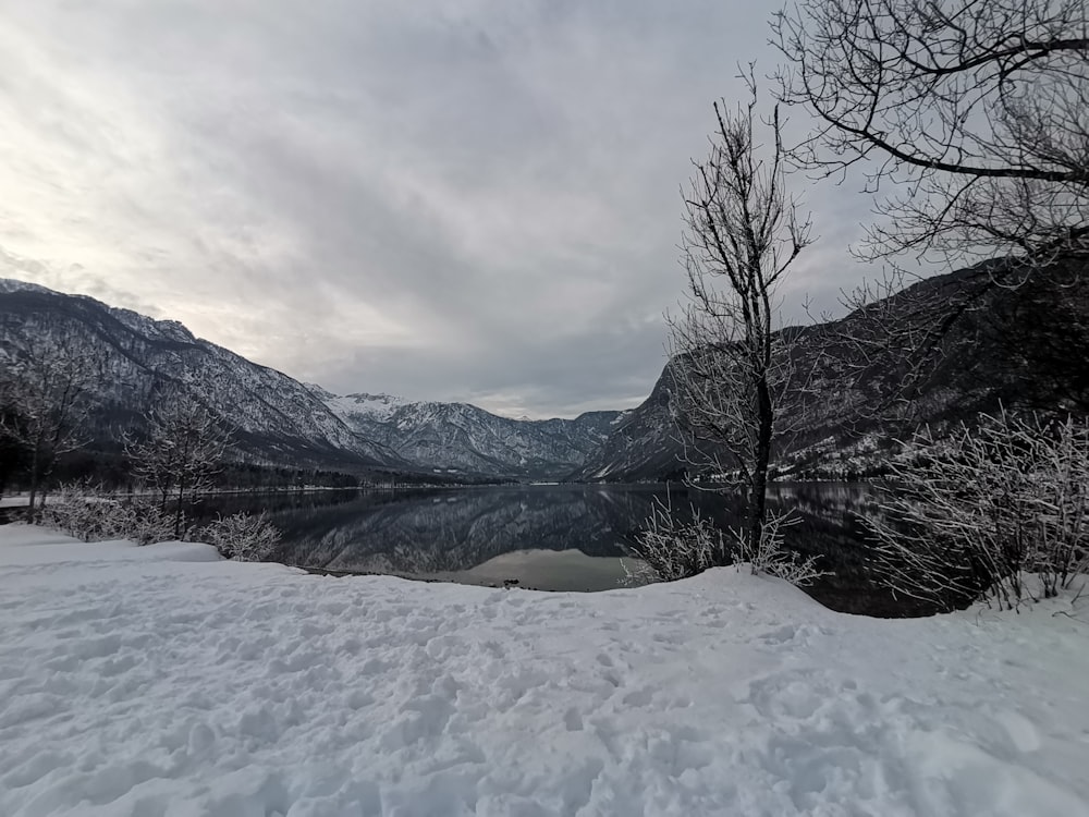 a lake surrounded by snow covered mountains under a cloudy sky