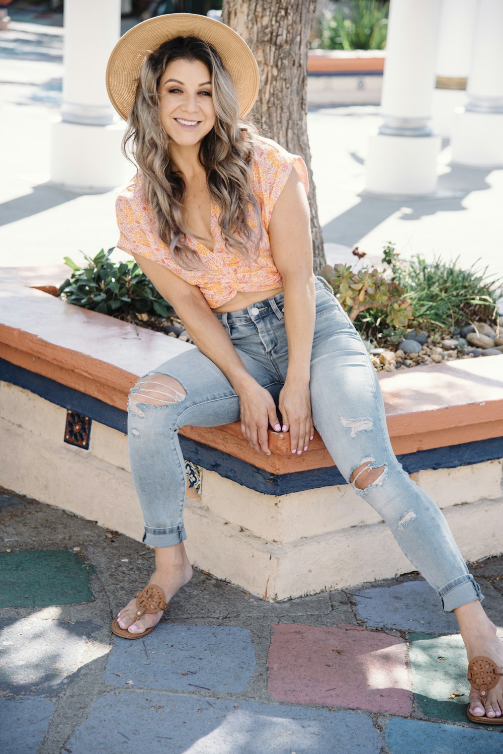 a woman sitting on a bench wearing a hat