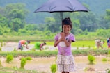 a little girl holding an umbrella in a field