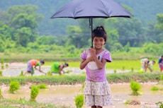 a little girl holding an umbrella in a field