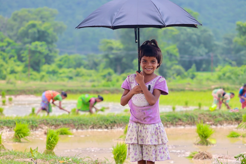 a little girl holding an umbrella in a field