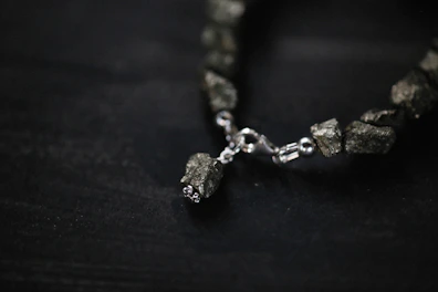 Minimalist black background showcasing a handcrafted silver bracelet with natural stones.