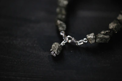 Durable bracelet made with strong threads and silver accents displayed on a natural stone.