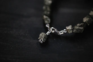 A close-up of a crystal diffuser bracelet resting on a smooth stone surface, highlighting its texture.