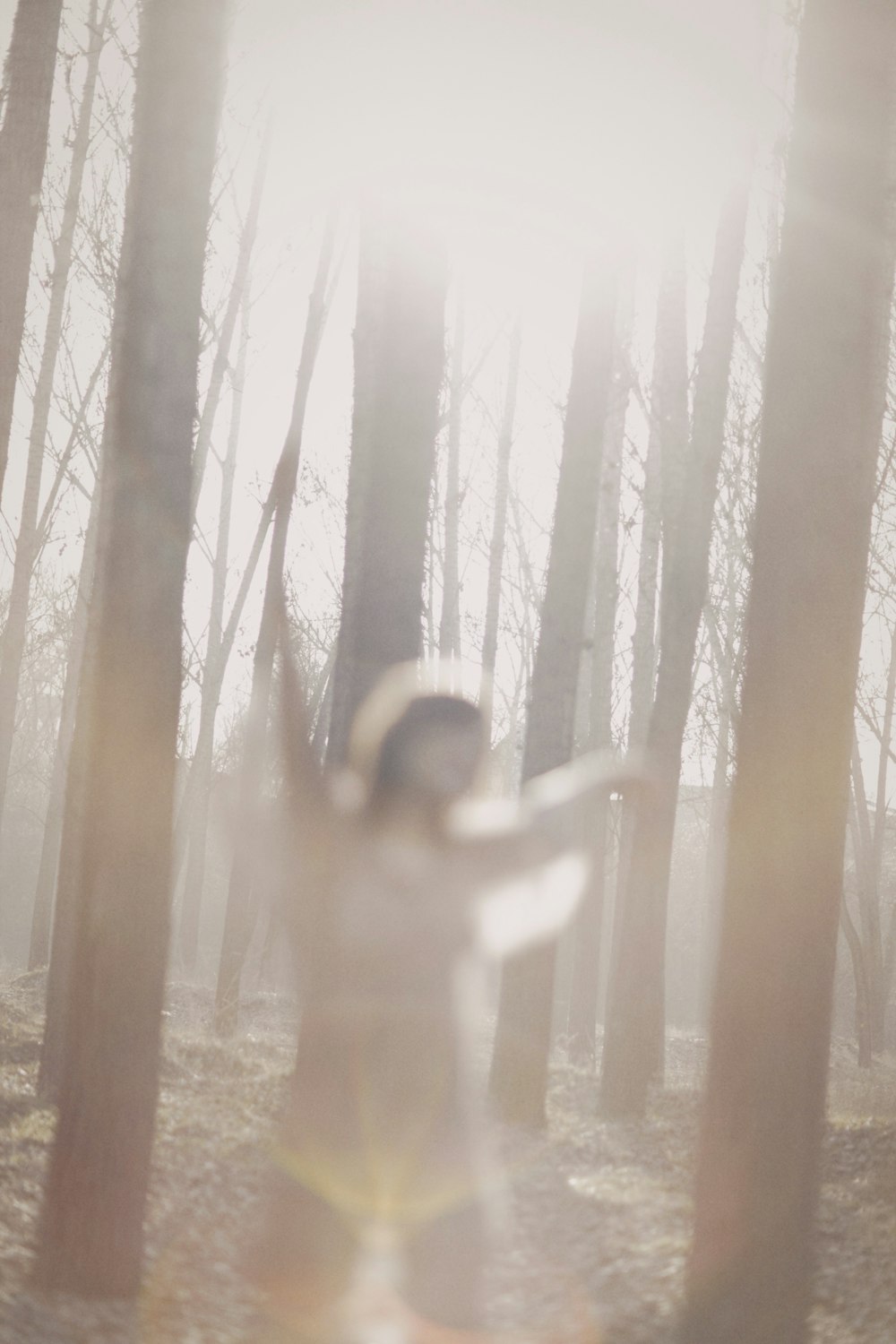 a woman standing in a forest with her arms outstretched
