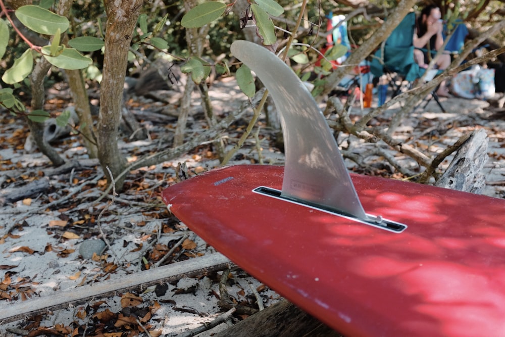 a red surfboard with a shark fin sticking out of it
