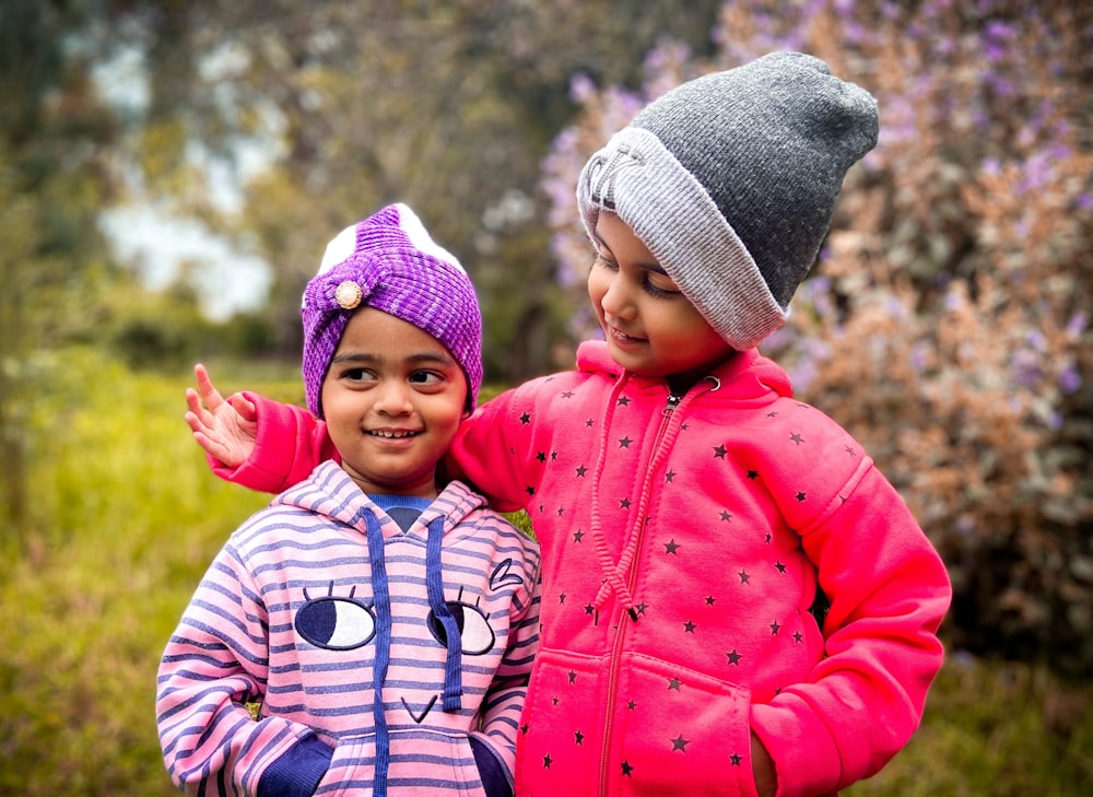 two little girls standing next to each other in a field