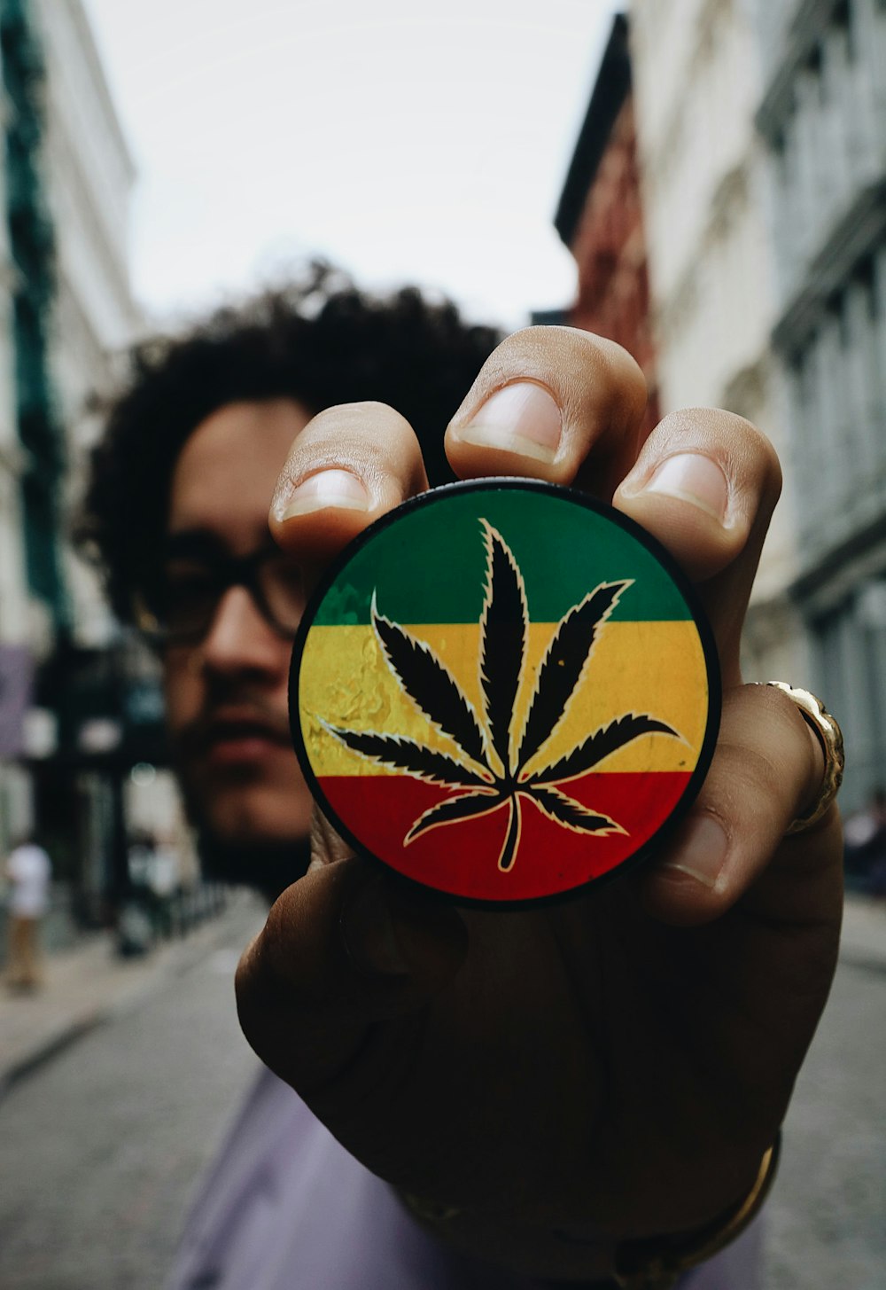a man holding up a badge with a marijuana leaf on it