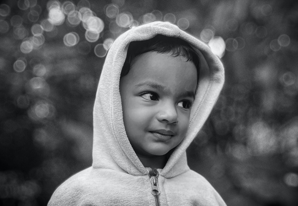a black and white photo of a young boy wearing a hoodie
